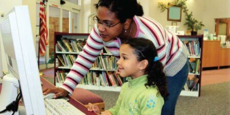 Mentor helping youth with activity on computer