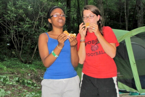 Reese and Katie eating smores and camping